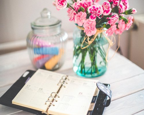 glass of water and an open notebook on a sunny desk
