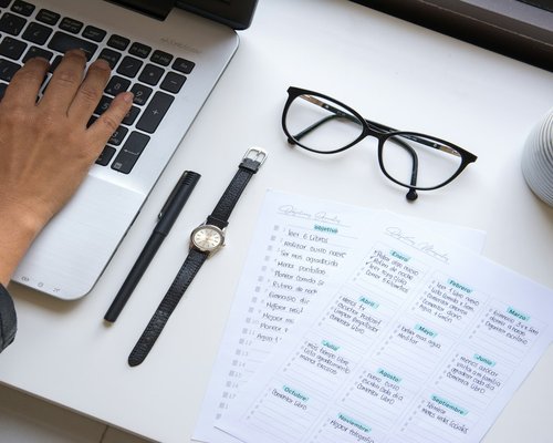 person organizing their schedule on a desk with a glass of water